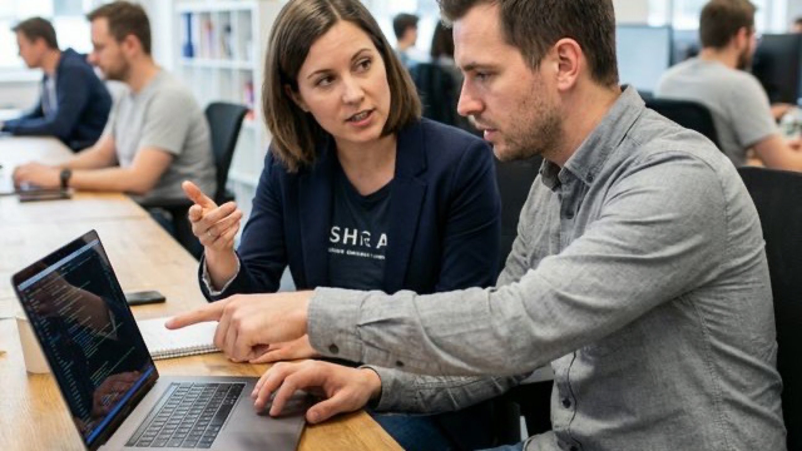 Two engineers reviewing code together in a modern office